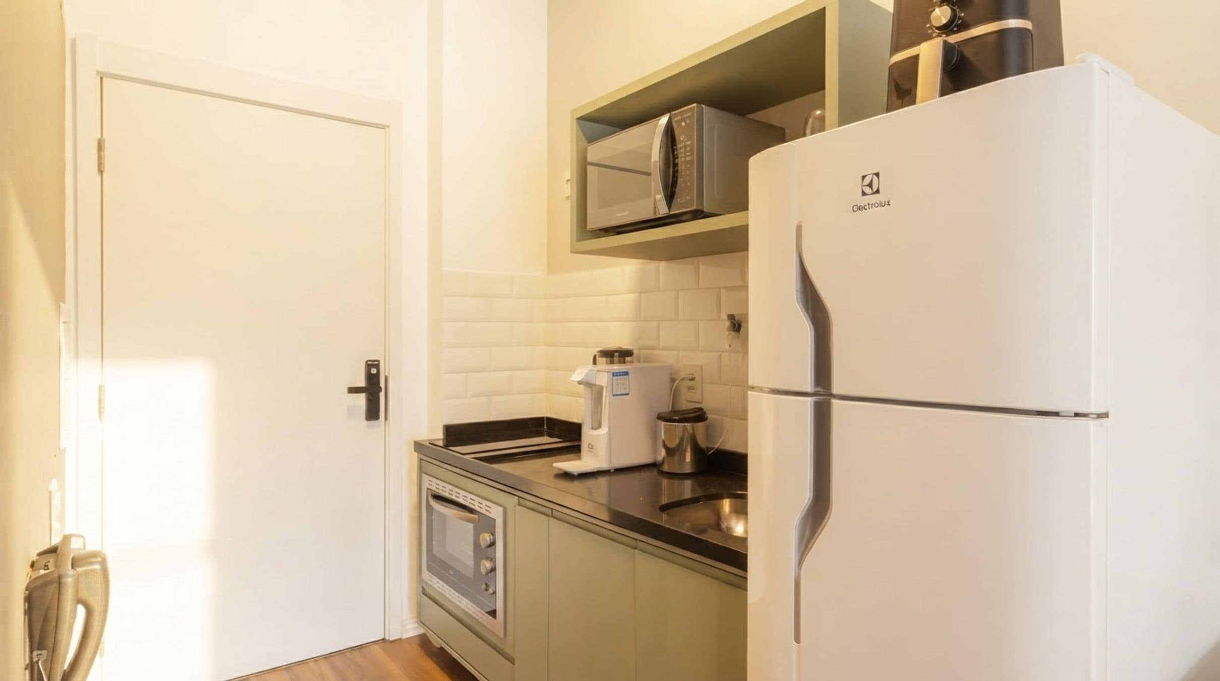 A compact kitchen with a built-in oven, a coffee maker, and a refrigerator.