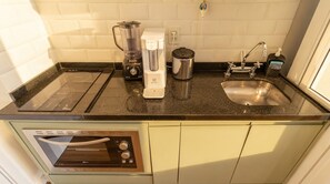 A compact kitchen with a built-in dishwasher, a coffee maker, a kettle, and a sink. - Studio com Varanda Perto do Metr em Pinheiros (São Paulo)