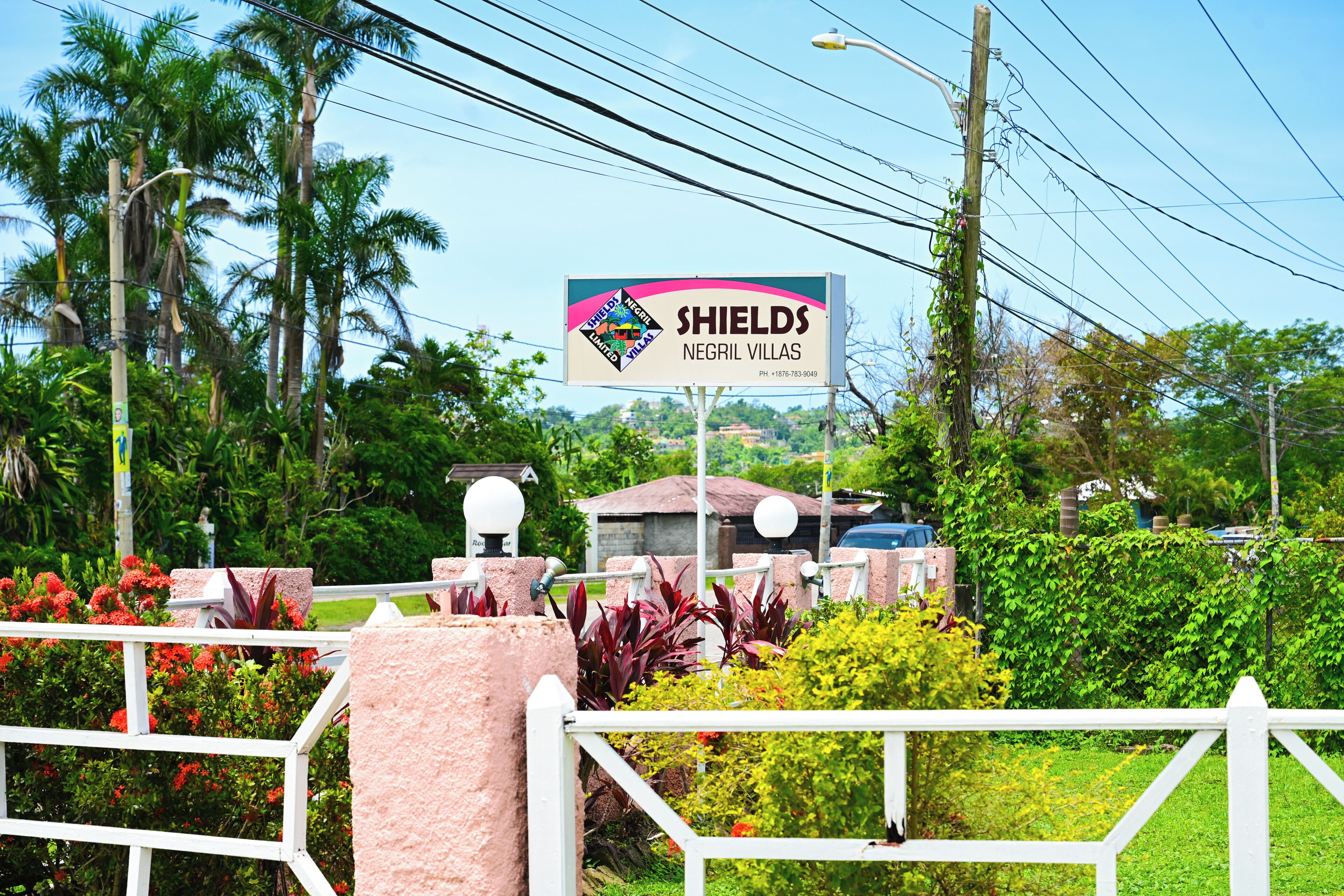 A sign for Negril Villas with a contact number.