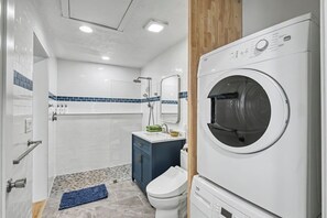 A modern bathroom with a built-in washing machine, a shower, and a toilet. - Cute clean cottage with modern amenities near downtown (McMinnville)