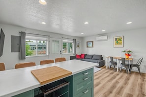 A modern kitchen with a large island, dining area with chairs, and a sofa. - Cute clean cottage with modern amenities near downtown (McMinnville)