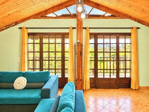 A room with a wooden ceiling, a blue sofa, and a view through large wooden doors.
