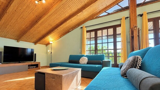 Un salon moderne avec un plafond en bois, un grand téléviseur à écran plat, un canapé bleu et une table basse.