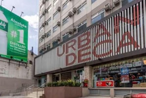 Un bâtiment sur lequel est apposée une grande enseigne indiquant « URBAN BEA » et un panneau publicitaire vert faisant la promotion de la marque « Absolute #1 Distilled Water Brand Philippines ».