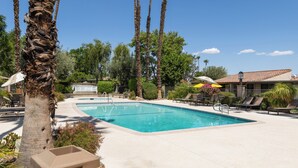 A rectangular swimming pool with a clear blue water surface, surrounded by a concrete deck. There are lounge chairs and umbrellas around the pool area. - Nacho's Place! (Palm Springs)