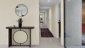 A hallway with a round mirror, a potted plant, and a console table. - Nacho's Place! (Palm Springs)