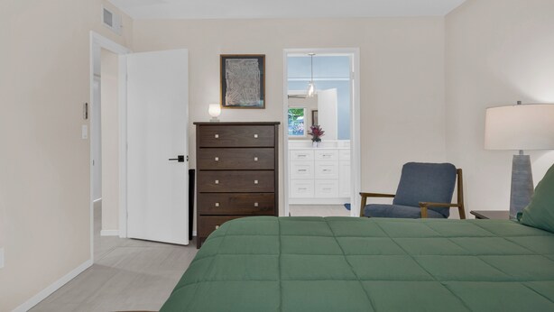 A bedroom with a bed, a dresser, a chair, and a ceiling fan. - Nacho's Place! (Palm Springs)