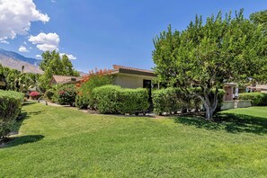 A residential area with a house featuring a red-tiled roof, surrounded by well-maintained lawns and various shrubs. - Nacho's Place! (Palm Springs)