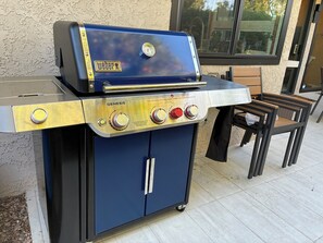 A portable Weber Genesis grill with a blue cabinet and a gas range. - Nacho's Place! (Palm Springs)