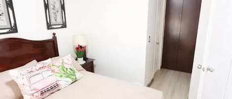A bedroom with a bed, a nightstand, a lamp, and a wardrobe.
