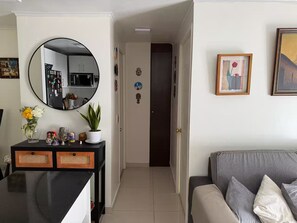 A living room with a sofa, a console table with decorative items, a mirror, and a door leading to another room. - Family 2BR 2 Baths, Walk to La Moneda-Free Parking (Santiago)