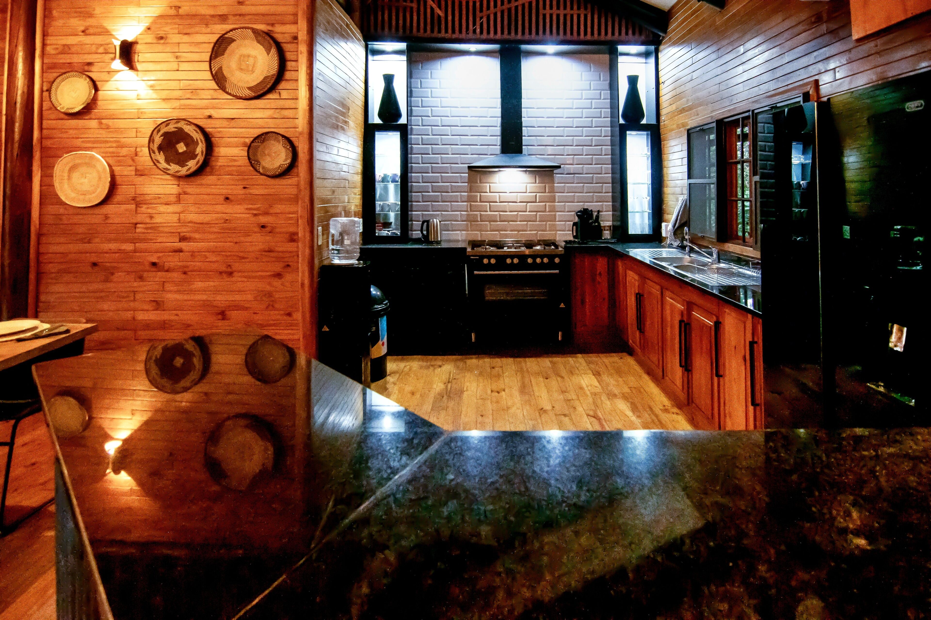 A kitchen with wooden walls, a brick backsplash, and a black countertop.