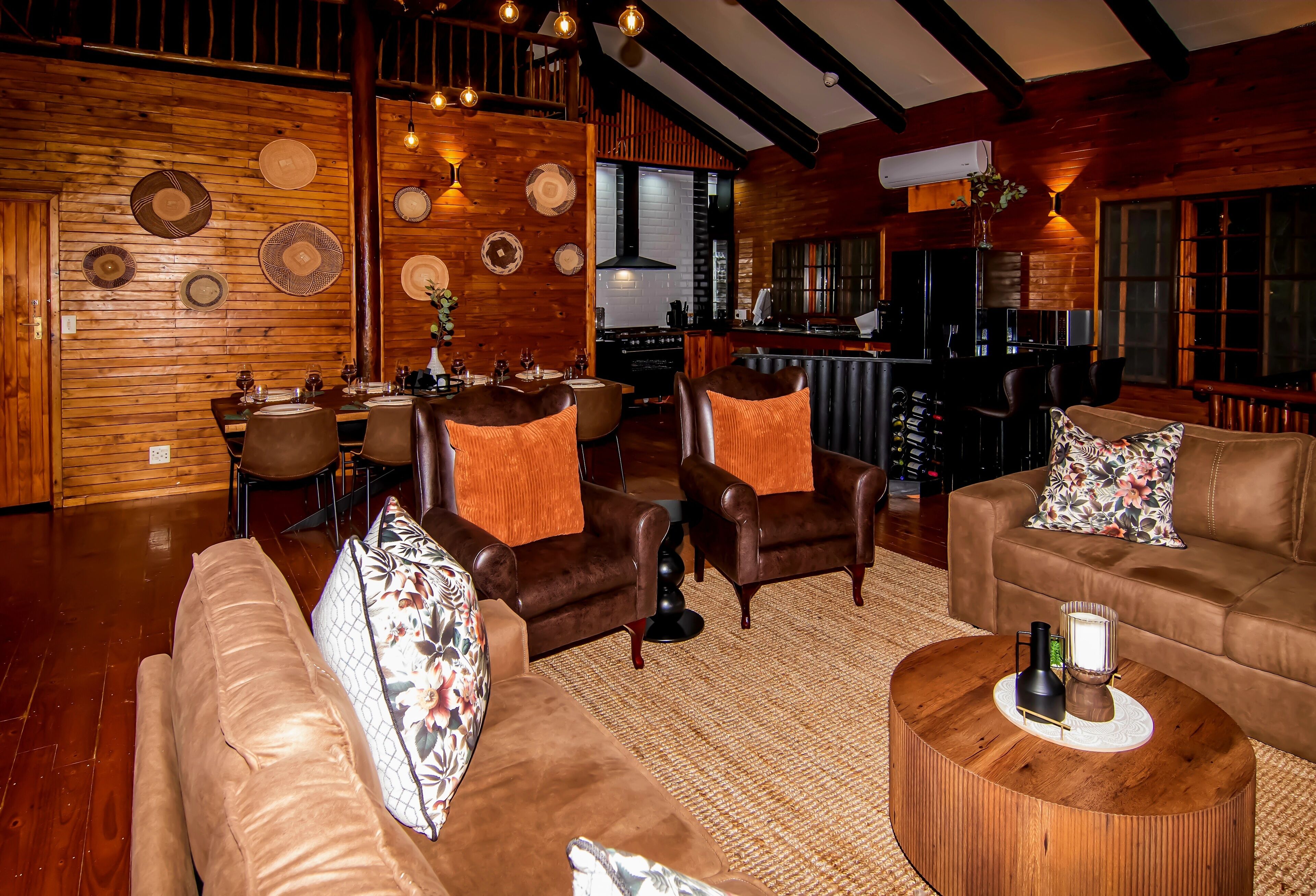 A cozy interior with a wooden dining area, leather sofas, and a bar.