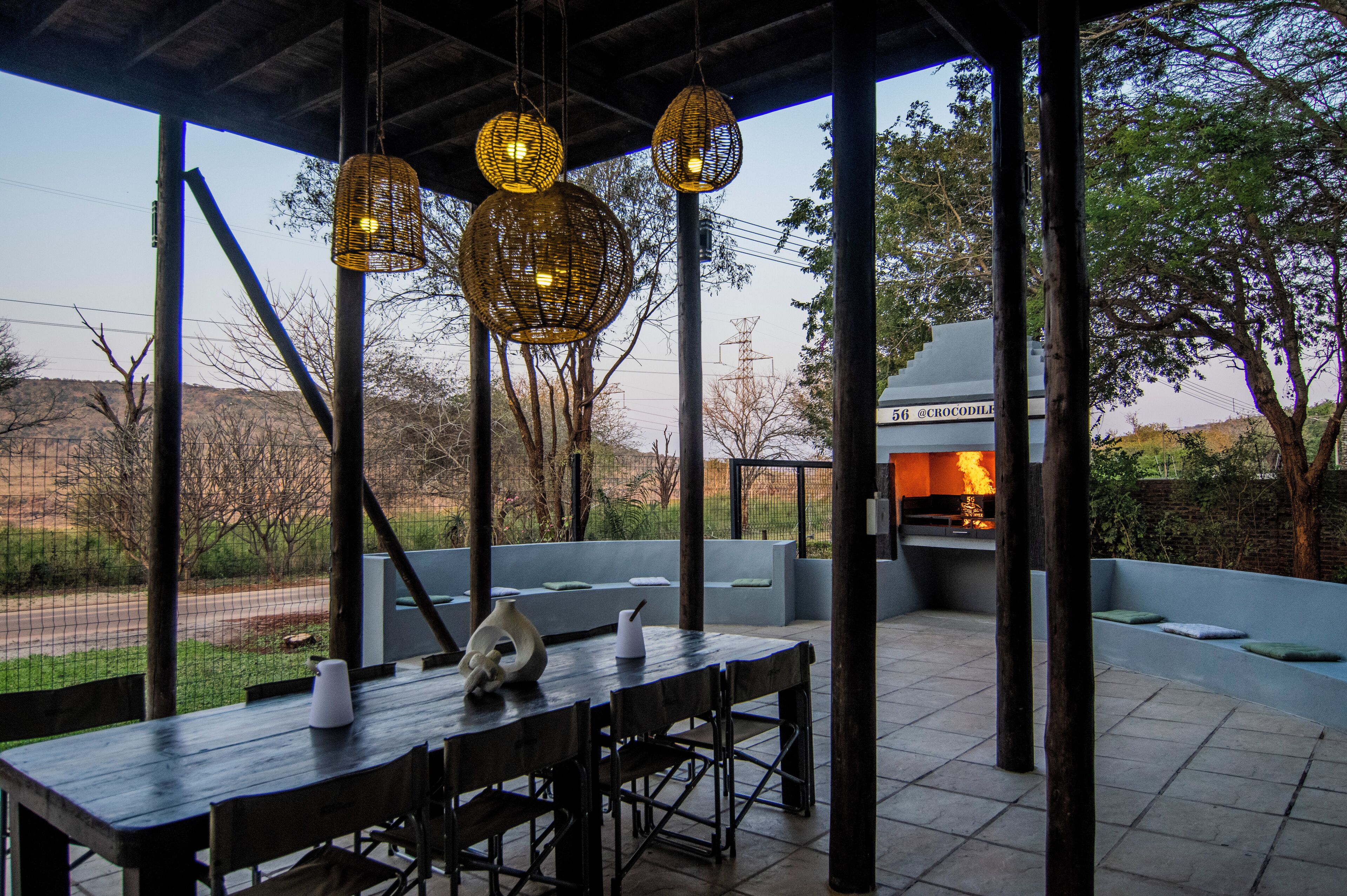 Un espacio exterior para comer con una mesa, sillas y luces colgantes.