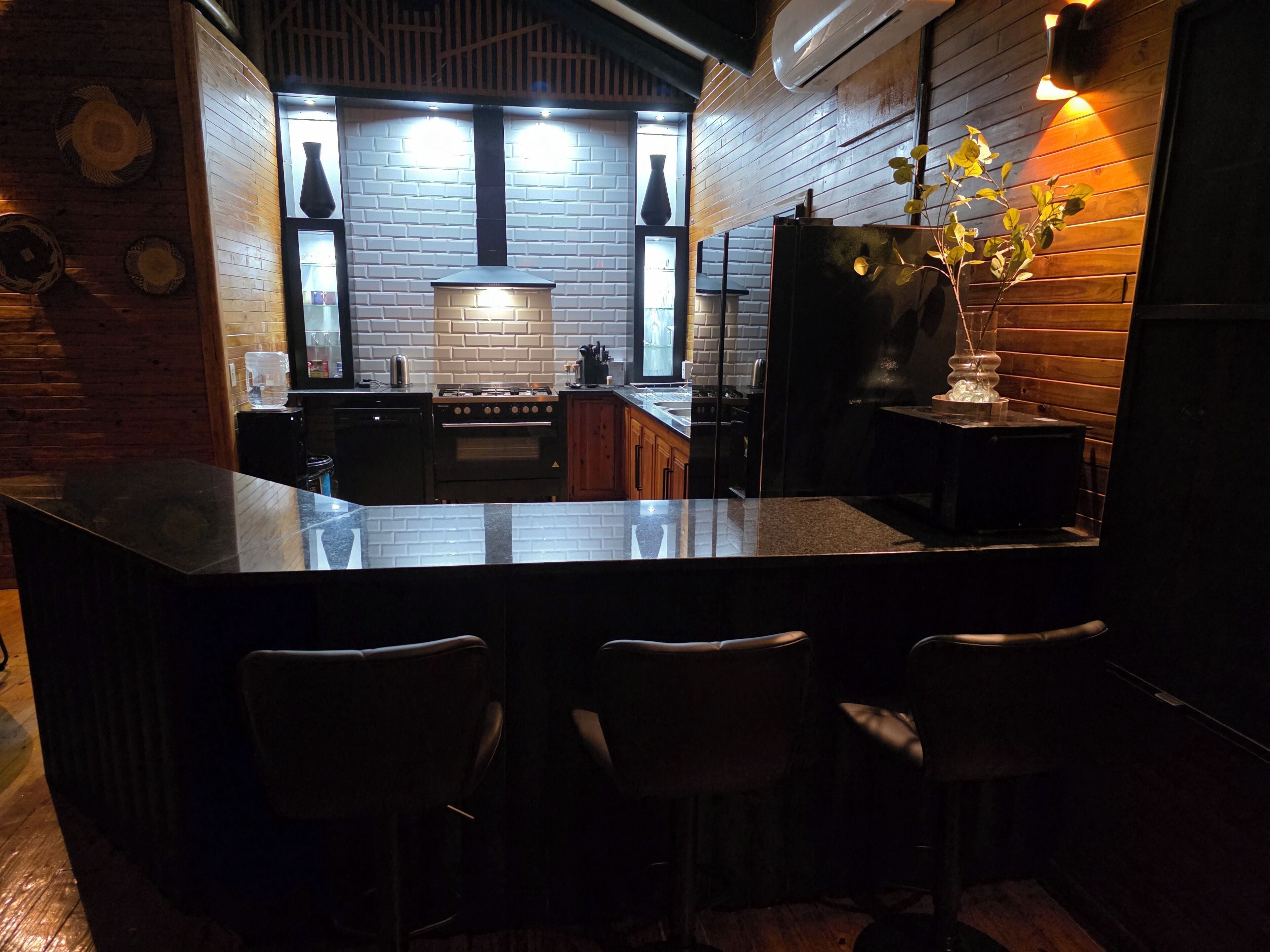A modern kitchen with a central island, bar stools, and a brick wall.