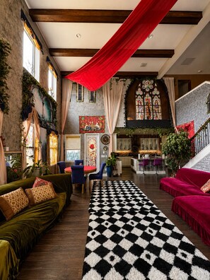Ein geräumiger Innenraum mit einem Schachbrettmuster-Teppich, einem grünen Sofa und einer Treppe, die in einen oberen Bereich führt.