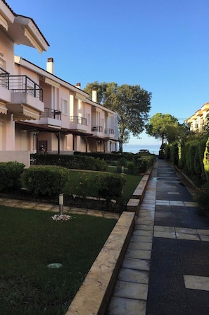 Una calle residencial con hileras de casas, cielo despejado y una masa de agua al fondo.
