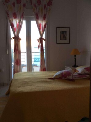 Ein Zimmer mit einem Bett, Vorhängen, einer Lampe und einem gerahmten Bild an der Wand.