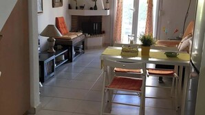 Een ruime woonkamer met een eettafel, stoelen, een bank en een open haard.