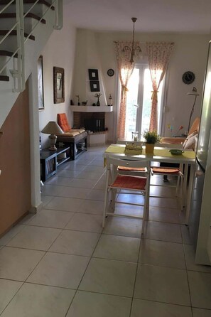 Ein geräumiger Wohnbereich mit Esstisch, Stühlen, einer Couch und einem Kamin.