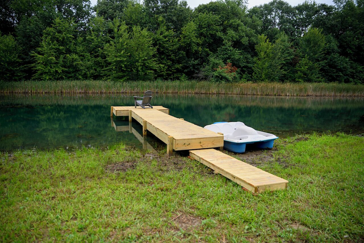 Une jetée en bois s’étendant sur un lac paisible, entourée d’une végétation luxuriante.