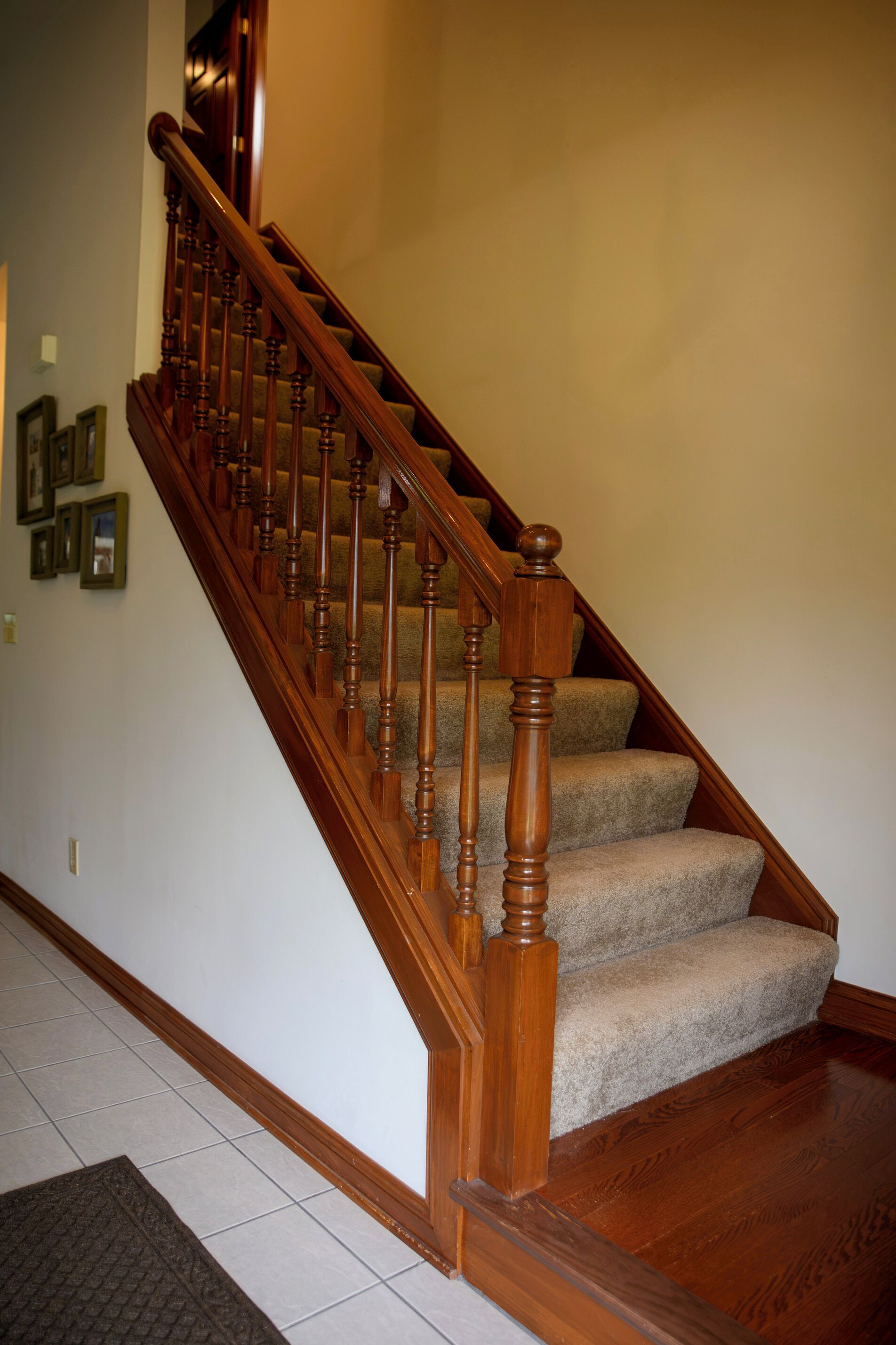 Un escalier en bois avec des marches recouvertes de moquette et une main courante.