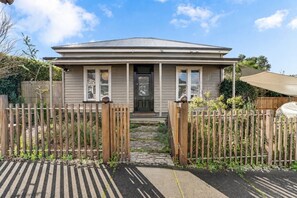 A single-story house with a front porch, a gated entrance, and a pathway leading to the door.
