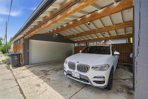 Un coche blanco estacionado en un garaje con techo de madera y puerta de garaje.