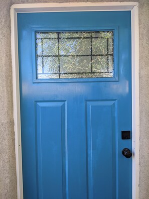 Une porte bleue avec une fenêtre et un sonnette.