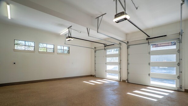 Eine geräumige Garage mit Betonboden, drei Fenstern und einer Garagentür.