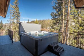 A hot tub on a wooden deck with a metal railing, surrounded by trees and a clear sky. - Peaceful Views | Hot Tub | Creekside Privacy (Winter Park)