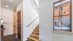 Ein modernes Interieur mit einer Treppe, einer Holztür und einem Fenster mit Blick auf ein Gebäude.