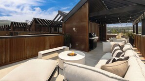 Eine Terrasse im Freien mit Grillbereich, Sitzgelegenheiten und Landschaftsblick.