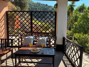 Eine Terrasse mit Tisch für zwei Personen, zwei Stühlen und Blick auf eine Hügellandschaft.