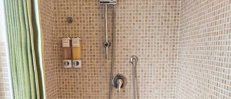 A bathroom with a shower, tiled walls, and a curtain.