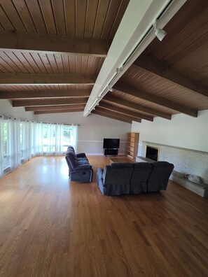A spacious living room with a wooden floor, a fireplace, and a television. - Spacious 4-bedroom ranch house in beautiful Mequon (Mequon)