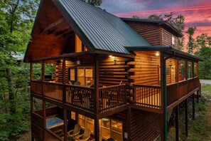 Une cabane en rondins avec un balcon, un jacuzzi et une vue sur la forêt.