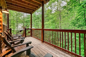 Eine Holzterrasse mit Bänken und Geländer, mit Blick auf einen Wald.