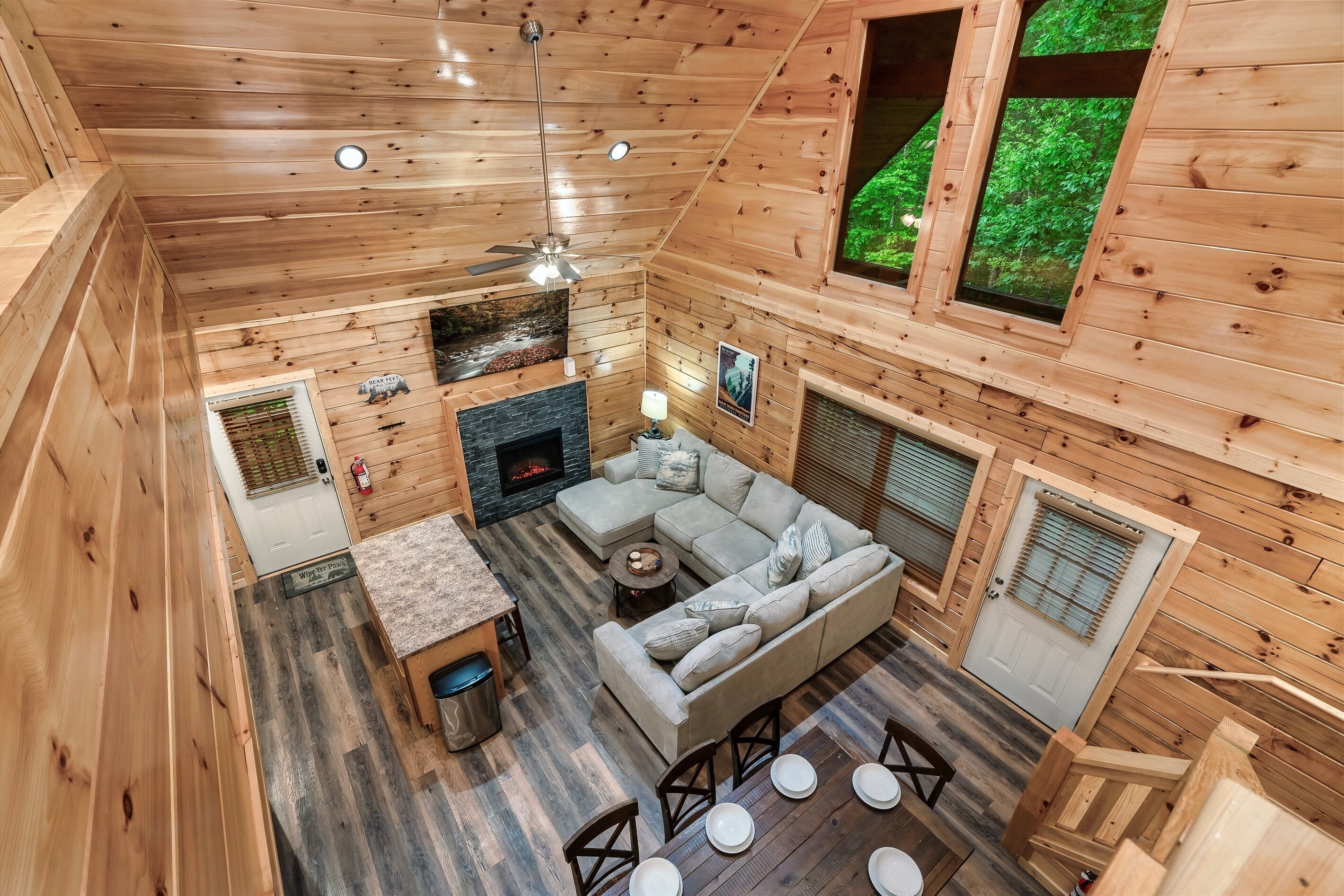 L’intérieur d’un chalet en bois comprend un espace de vie, une cheminée et de grandes fenêtres.