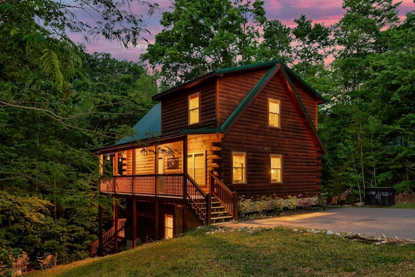 Une cabane en rondins dotée d’un balcon, d’un escalier et d’une véranda.