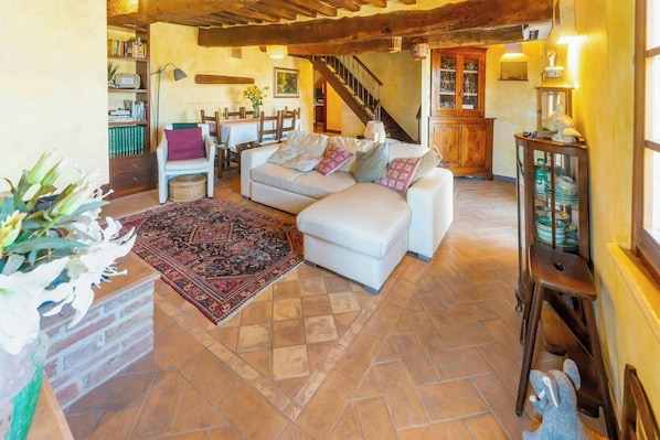 Una sala de estar acogedora con un sofá blanco, un tapete estampado y una escalera que sube.