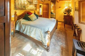 Un dormitorio con cama, mesita de noche, lámpara, espejo y puerta.
