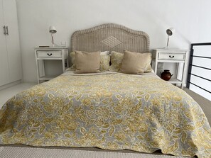 A bed with a patterned bedspread, two bedside tables with lamps, and a nightstand with a vase. - Central | 1 Bed | Loft | Pool | Views (Cape Town)