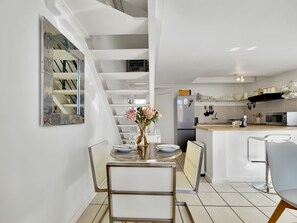 A modern kitchen with a dining area, featuring a staircase, stainless steel appliances, and a minimalist design. - Central | 1 Bed | Loft | Pool | Views (Cape Town)