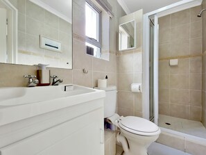 Uma casa de banho moderna com uma sanita branca, lavatório e zona de duche.