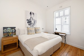 A bedroom with a bed, bedside tables, a desk, and a window. - Two Bed Home | Fresnaye | Secure | Spacious | BBQ (Cape Town)