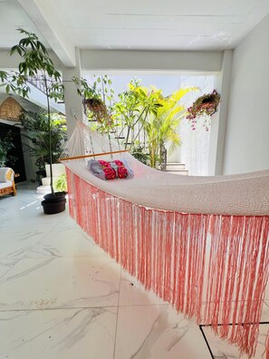 A spacious indoor area with a seating area featuring a white couch and a hanging hammock. - Bright apartment with a small pool, just 15 minutes from downtown Oaxaca. (Oaxaca de Juárez)