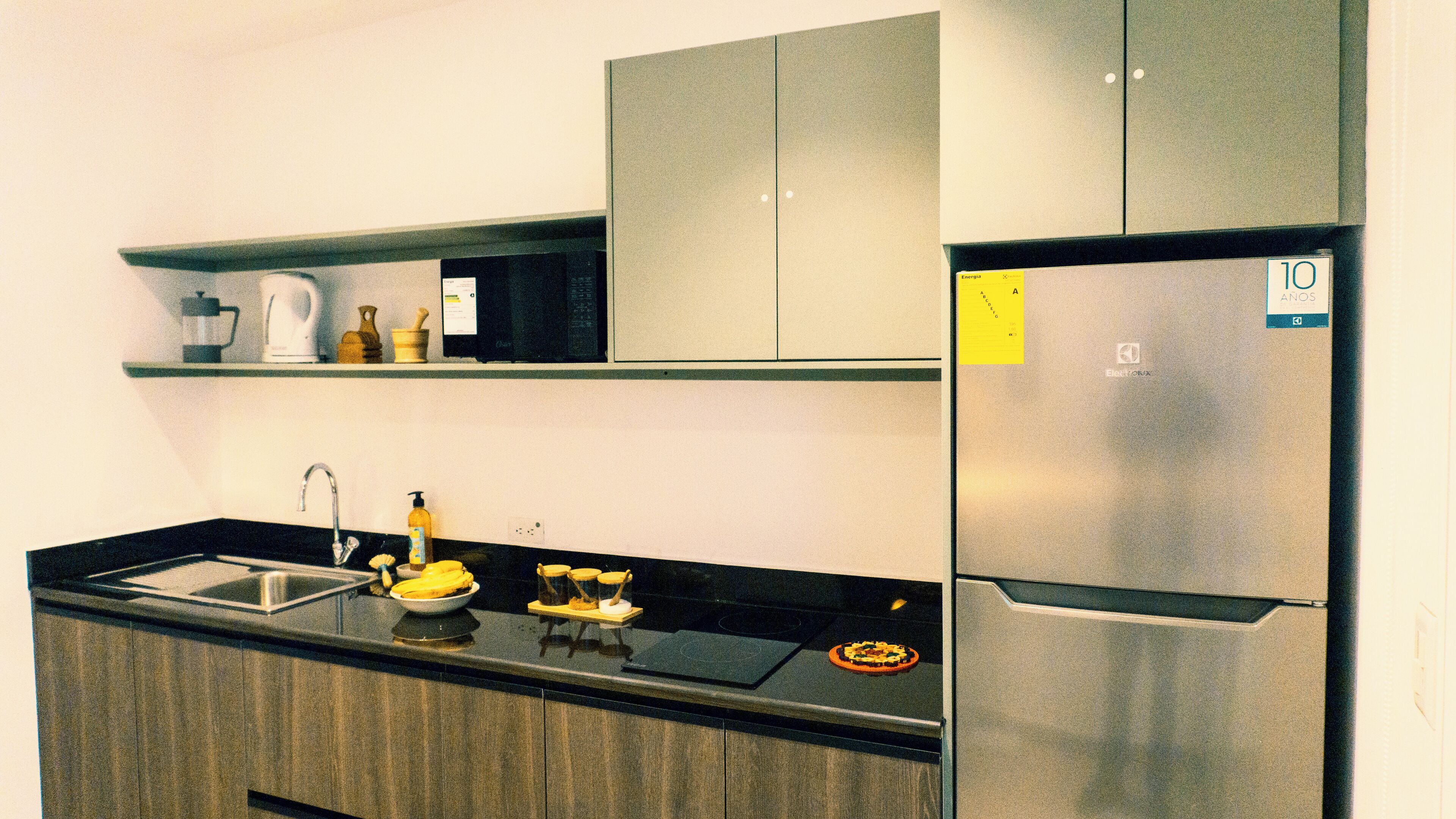 A modern kitchen with a stainless steel refrigerator, a black countertop, and a built-in oven.