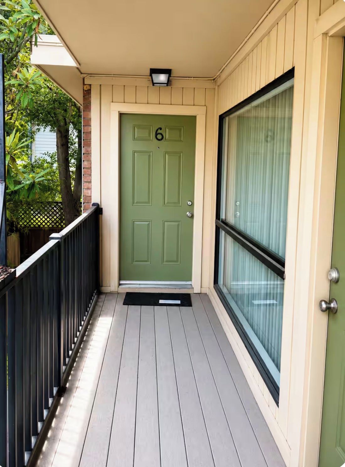 A green door with the number 6, a black metal railing, and a glass door to the right.