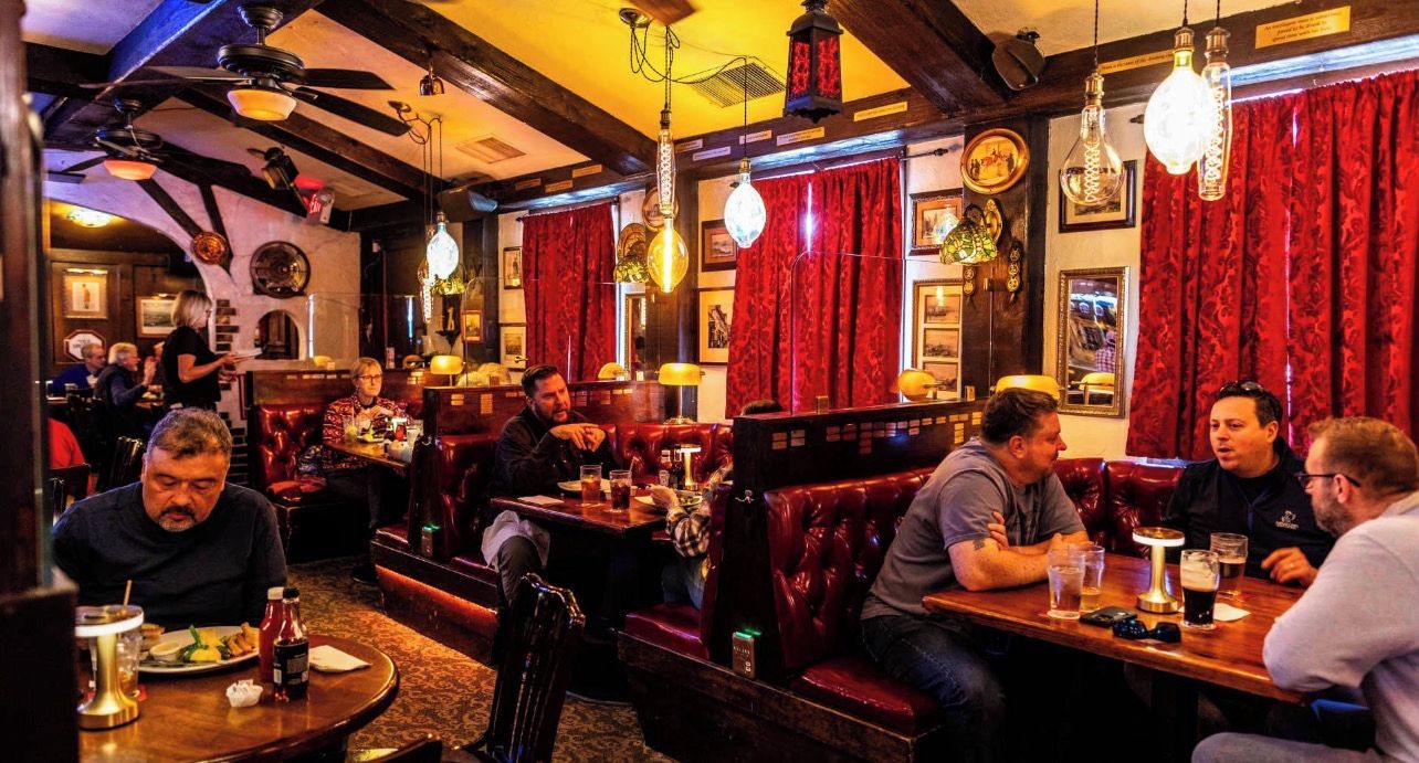 A restaurant interior with booths, tables, and hanging light fixtures.